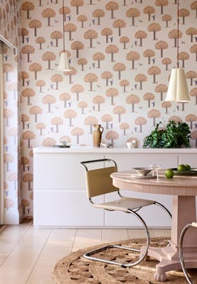 Dining room featuring pale pink tree print wallpaper (Rodney Street - Masquerade) with a white cabinet, dining room table and chairs.